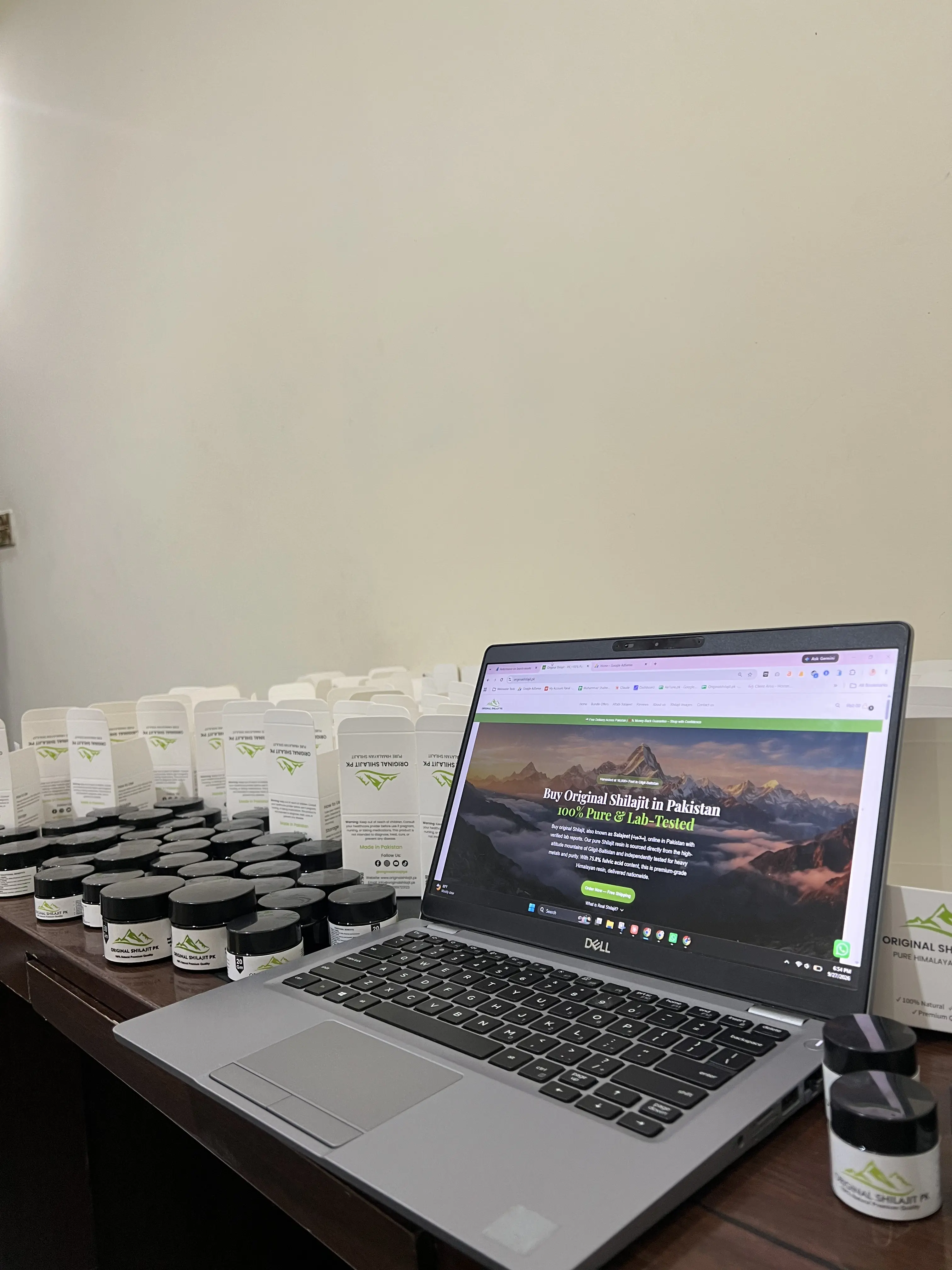 Original Shilajit PK jars and boxes next to a laptop showing the Original Shilajit PK website
