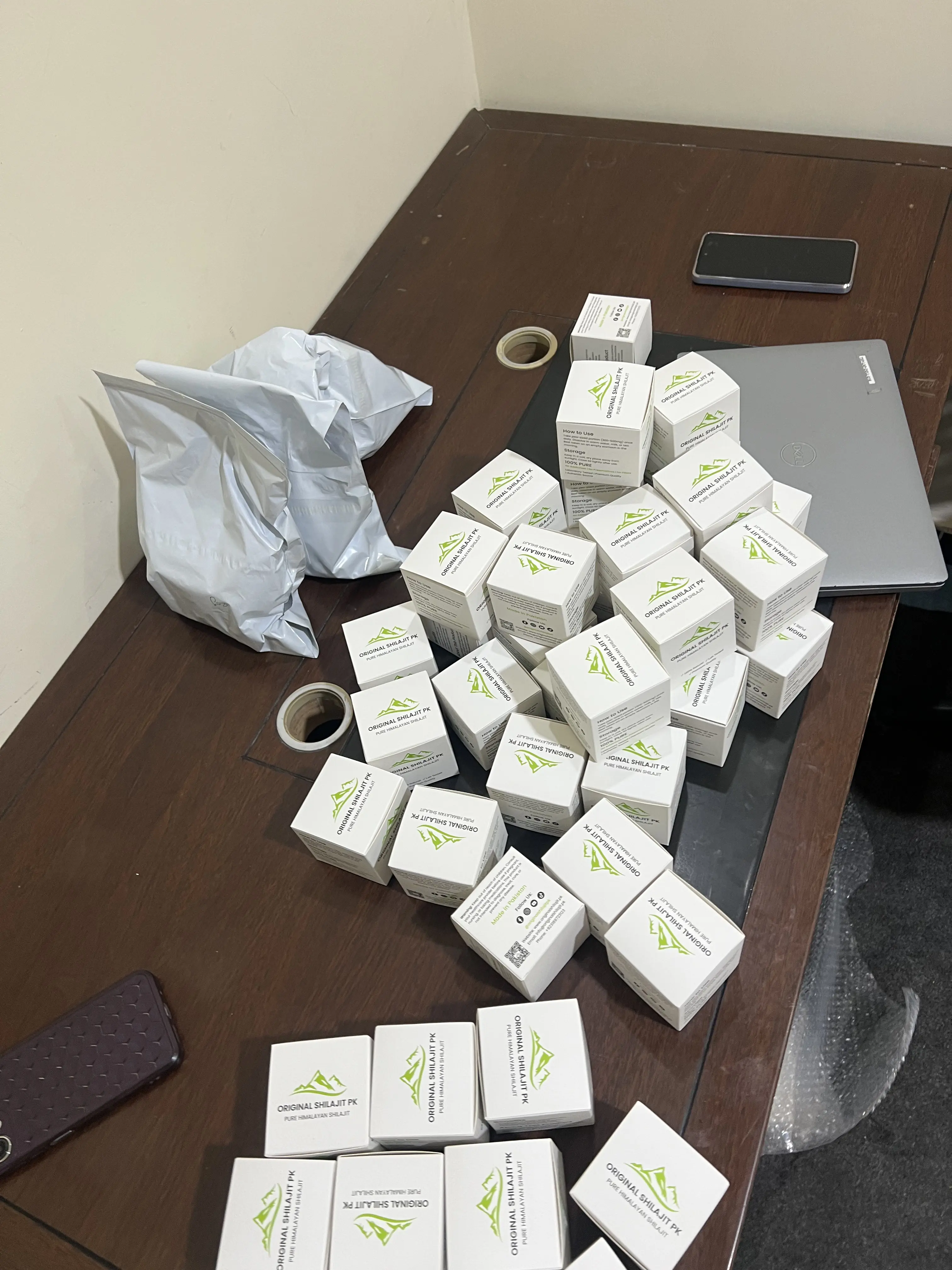 Pile of boxed Original Shilajit PK jars on a desk, ready to ship